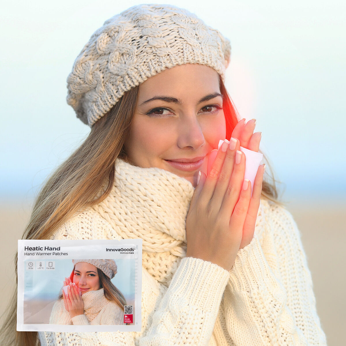 Woman warmly clothed in winter on the beach kätesoojendaja